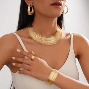 Detail of a multilayered gold choker set with matching earrings and bracelets on a model
