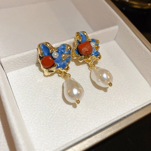 Detail of baroque pearl drop earrings with blue enamel and orange gems on gold base