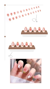 Pink gradient press-on nails with white floral patterns and green French tips on hands