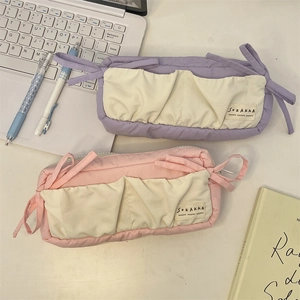 Detailed view of purple and pink canvas pencil cases with cream-colored outer pockets