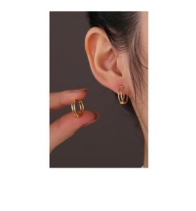 Detailed view of double-hoop 14K gold plated silver earrings worn on the earlobe