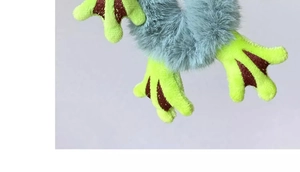Detailed macro view of soft plush green frog feet attachment on a fuzzy blue hair tie