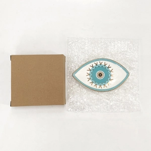 Macro shot of evil eye ceramic tray with brown corrugated box and protective film