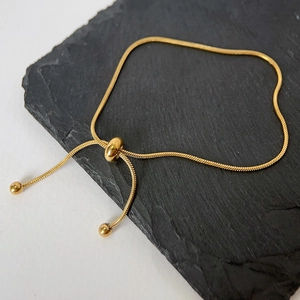 Detail of adjustable snake chain bracelet with golden finish and sliding bead closure