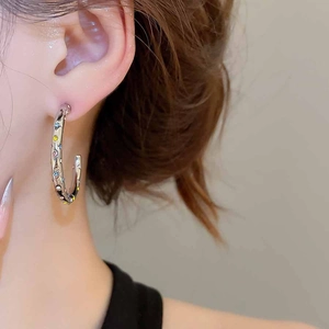 Détail de boucles d'oreilles en C argentées avec zircons colorés étincelants