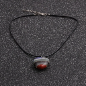Collana con pendente a cuore in cristallo multicolore e cordino nero su fondo scuro
