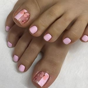 Close-up of pink press-on toenails with butterfly patterns and glitter on white fabric