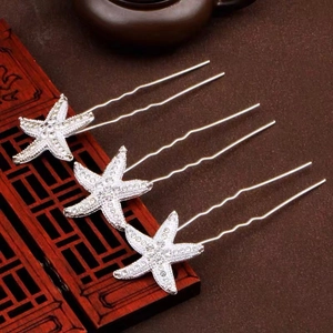 Three silver starfish U-shaped hairpins with rhinestones placed on a wooden box