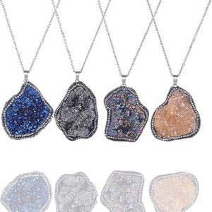 Detalle de cuatro colgantes de geoda de ágata natural en azul, plata y champán sobre fondo blanco