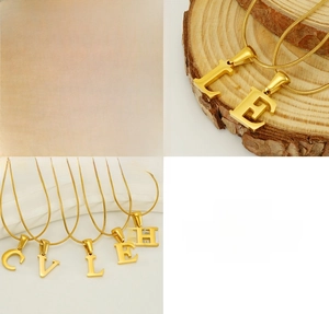 Macro detail of gold initial letter pendants with mirror polishing on snake bone chain