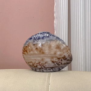 Close-up of oval marble resin clutch showing blue and cream stone texture and glossy finish