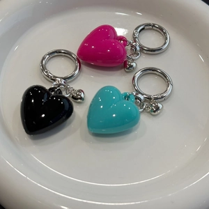 Close-up of heart pendants in pink, black, and teal on a white plate with metal rings