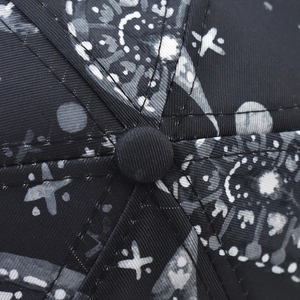 Close-up of the six-panel crown stitching and central button on a paisley baseball cap