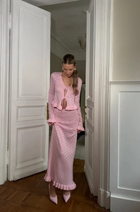 Detail of pink knitted two-piece set featuring hollow-out lace-up cardigan and midi skirt