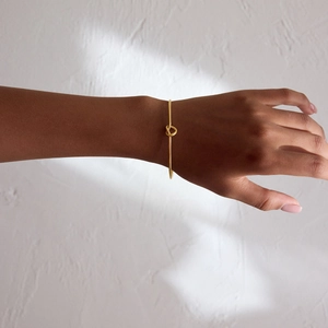 Close-up detail of a minimalist 18K gold knot design stainless steel open cuff bracelet