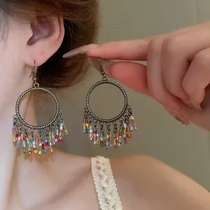 Bohemian style bronze hoop earrings with colorful beaded fringe on a female model