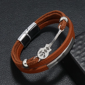 Detail of a brown multi-layer leather bracelet featuring a silver guitar pendant charm
