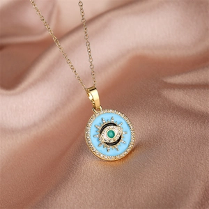 Close-up of golden evil eye pendant with blue enamel and zircons on silk fabric