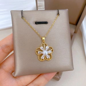 Close-up of golden hollow flower necklace pendant featuring central pearl and crystals