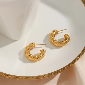 Detail of twisted 18K gold plated stainless steel thick hoop earrings on silk fabric