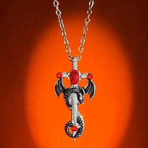 Gothic dragon cross necklace with red rhinestones and sword pendant on orange background