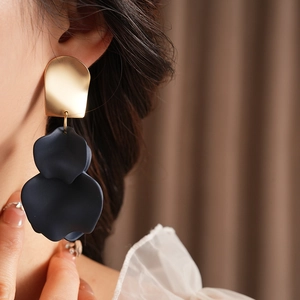 Close-up of irregular gold metal and matte dark blue layered flower petal earrings