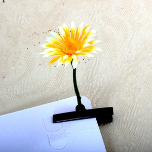 Detailed close-up of a realistic daisy hair clip with white petals on a green stem
