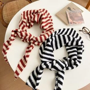 Flat lay of retro striped knit shawls in red and black on a white table setting