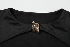 Detail of elegant black dress with a golden metal interlocking ring on the neckline