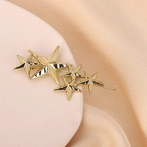 Detailed close-up of golden multi-star metal hair clip on elegant beige silk display