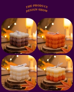 Close-up of stacked pumpkin-shaped scented candles in autumn decor with warm fairy lights