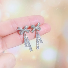 Close-up of silver bow tassel earrings with sparkling rhinestones and vertical drop
