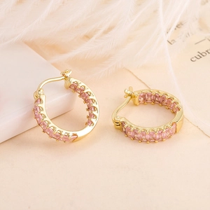 Detail of C-shaped gold hoop earrings with row of pink rectangular-cut zircons
