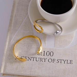 Close-up of dual-tone minimalist open bangles in gold and silver finish with drip design