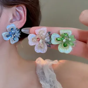 Floral crystal stud earrings with colorful petals and pearls shown on a model
