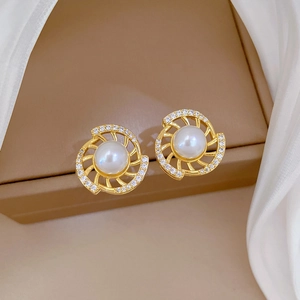 Detailed shot of gold pearl earrings with a spiral diamond-encrusted design on silk