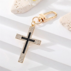 Detail of gold cross keychain with black enamel center and sparkling rhinestones