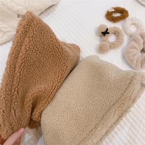 Close-up of soft faux lamb wool fisherman hats in brown and beige with plush texture