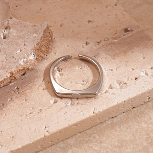 Macro shot of silver minimalist square open ring on beige stone texture surface