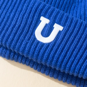 Gros plan d'un bonnet en maille côtelée bleue avec une broderie blanche de la lettre U