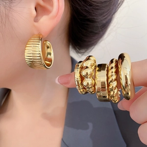 Detailed view of golden textured hoop earrings and multi-style minimalist rings on hand