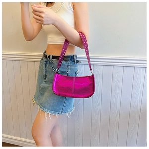 Detail of metallic rose pink underarm bag with silver rivets worn by model in white top