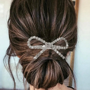 Detail of silver bow hair clip with rhinestones worn on a low bun hairstyle