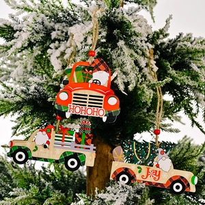 Three wooden Christmas truck ornaments with gnomes hanging on a snowy tree branch