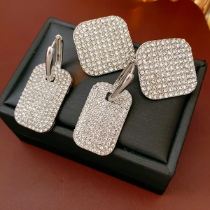 Close-up of sparkling square rhinestone earrings set in silver metal on black jewelry box