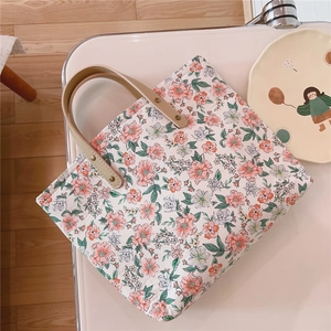 Close-up of floral tote bag featuring leather handles with reinforced metal rivets