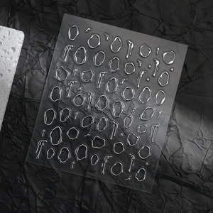 Detail view of 3D liquid metal nail stickers with silver irregular shapes on black background