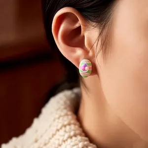 Pink and green striped oval earrings with colorful beads shown on model's ear