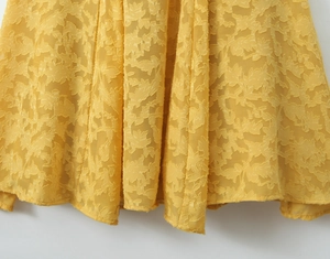 Detail aus gelbem Stoff mit Blattstickerei und strukturiertem Meerjungfrau-Kleid