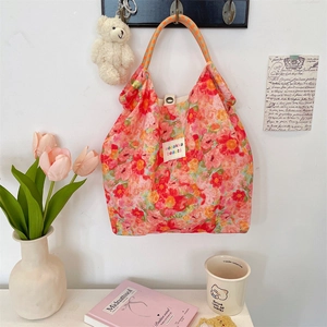 Detailed view of floral tote bag with bright red flowers and woven check handles